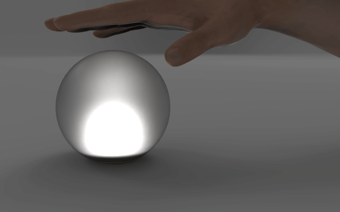 This image shows the light in a darker environment with a hand. The hand is moving up and down, pressing down on the sphere. The sphere springs back up, and it turns on or off every time the hand taps it.