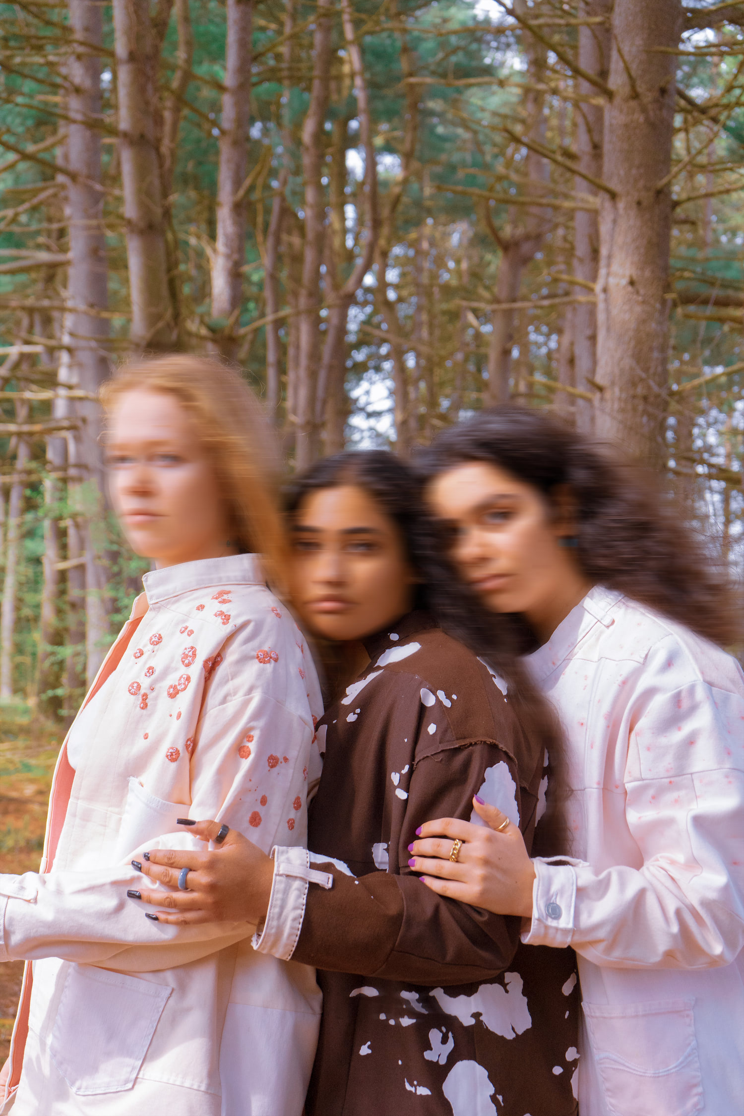 Three models wearing hand stitched jackets, leaning on each other and looking toward the camera.