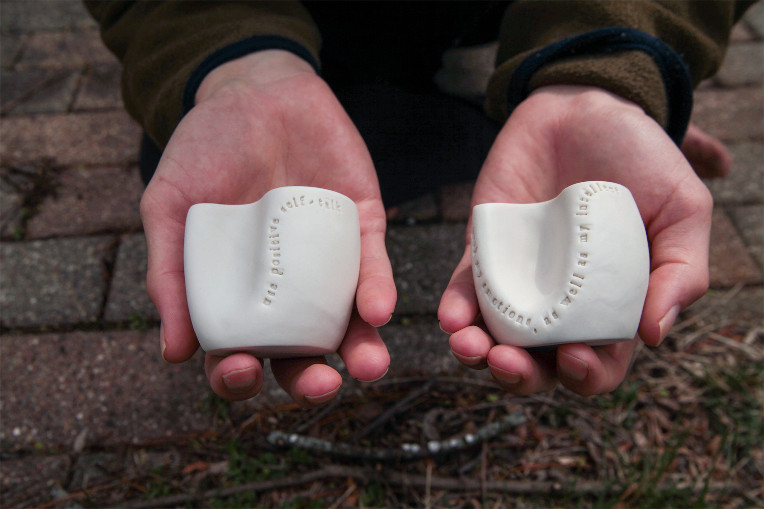 Two hands each holding a cup.  The cup on the left: 