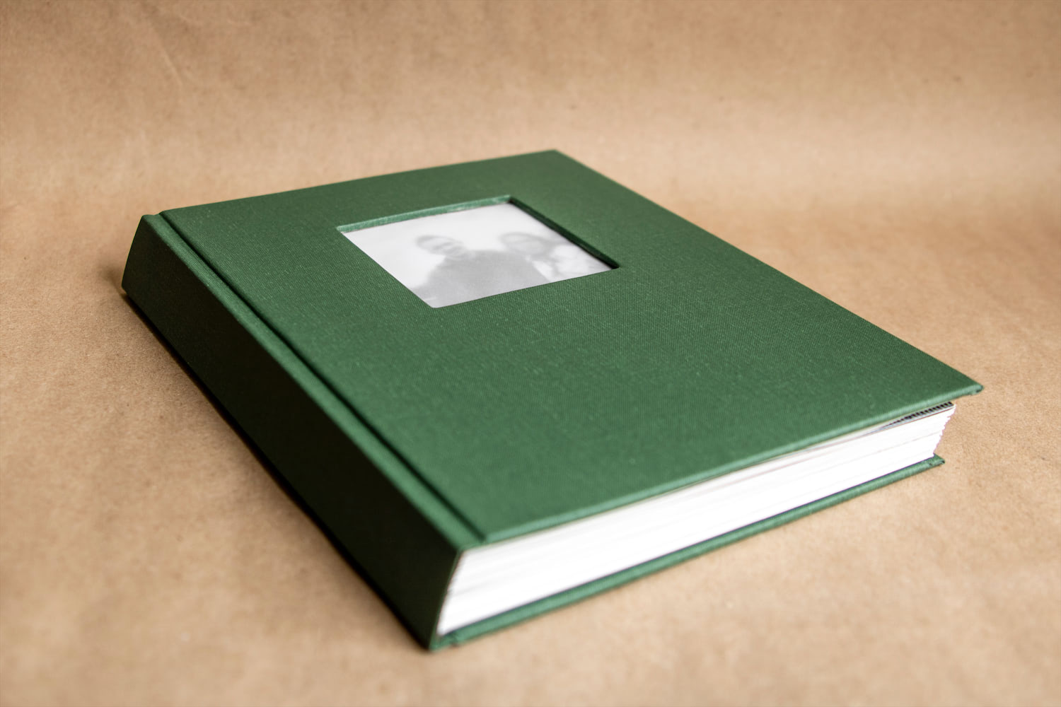 A side view of the drum leaf style book with green bookcloth and an image of two people on the cover.