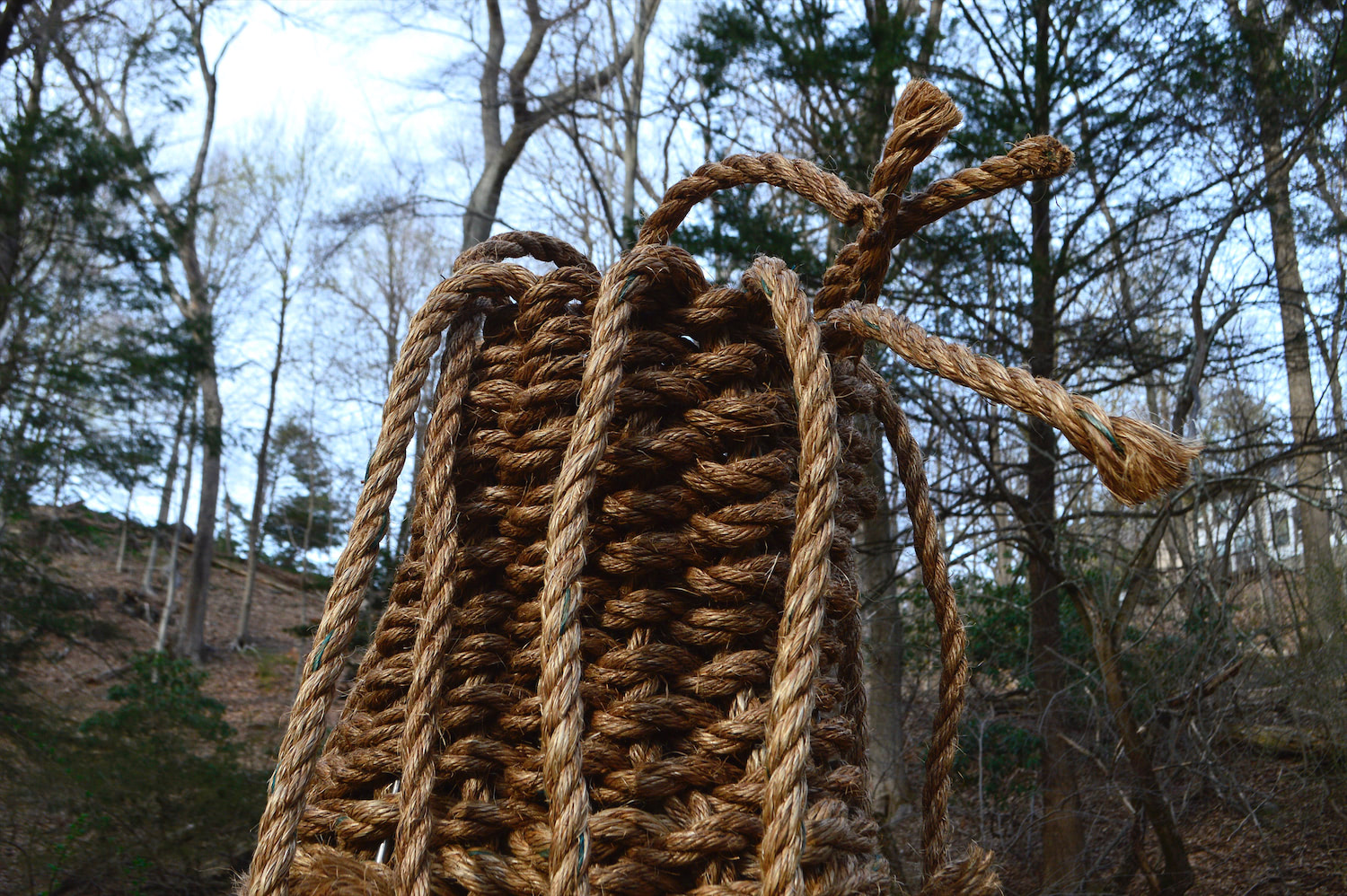 This detail shot captures the top few rows of the basket as well as the dangling frayed warp. The edges of the vertical rope segments are not tucked into the basket, allowing for the weaving process to continue infinitely as additional material is inserted into the structure.
