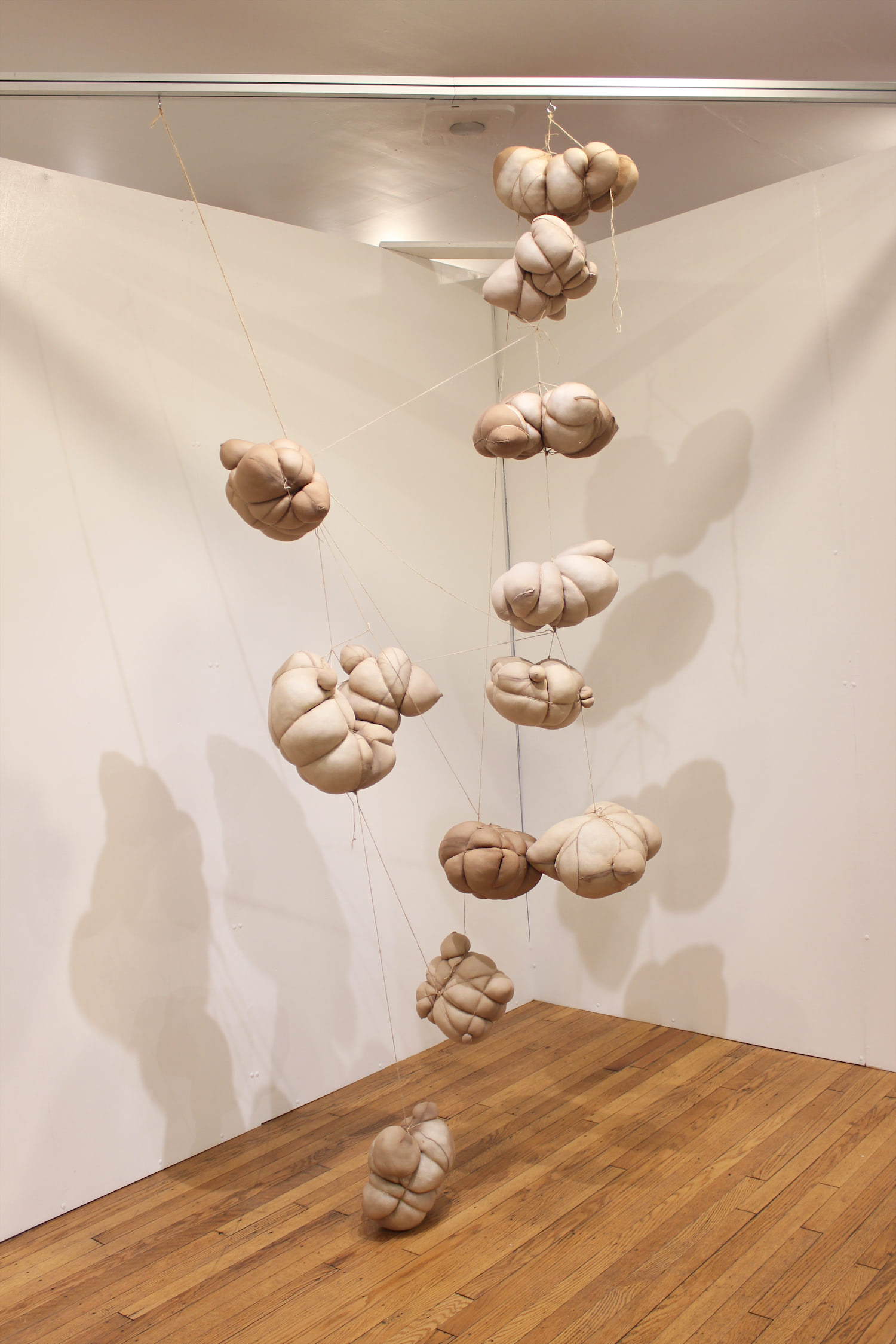 This image shows the other hanging sculpture within the installation. Multiple rounded soft sculpture forms are wrapped tightly to create the visually constricted object. These sculptures are also connected together with twine.