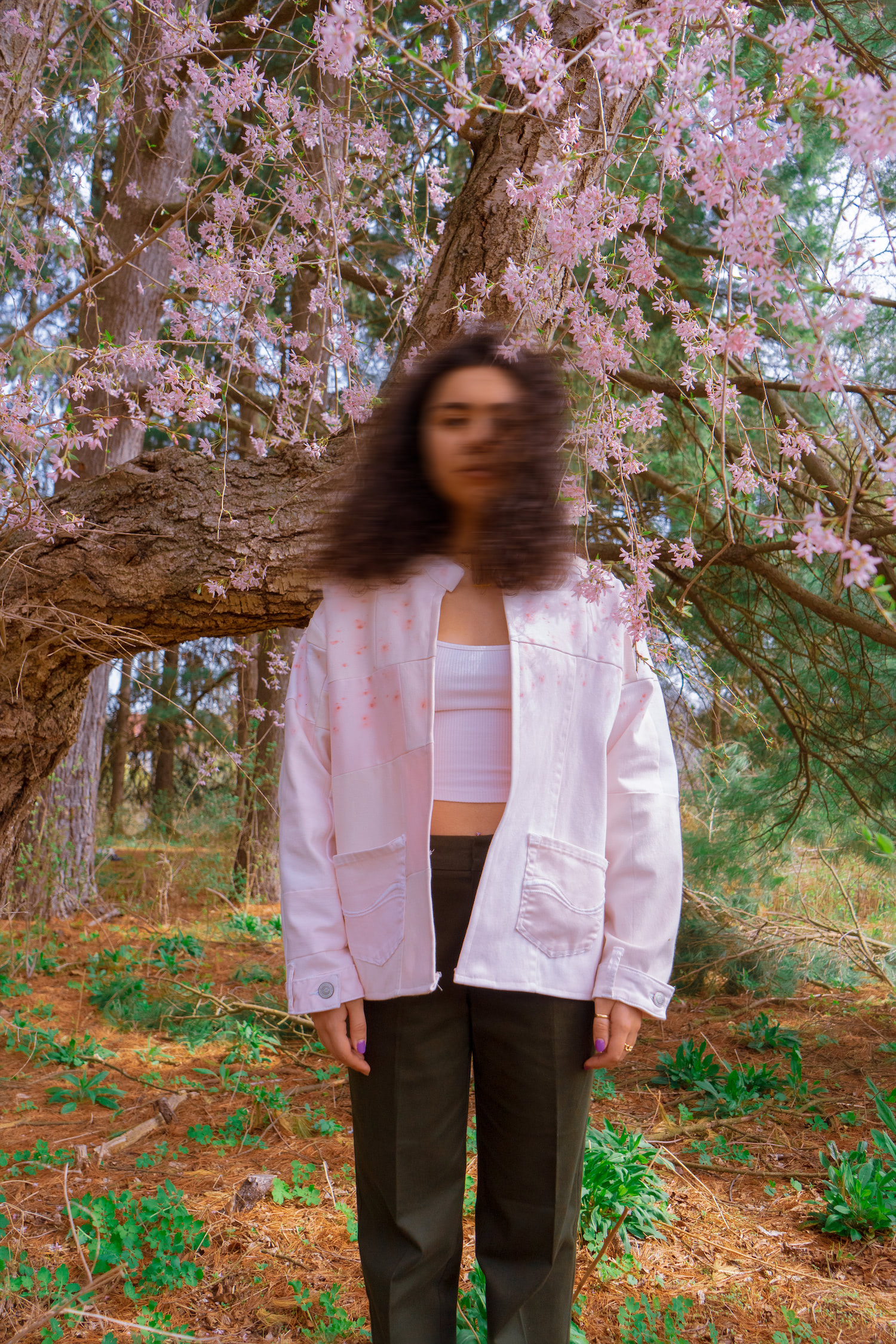 Model wearing acne jacket, facing camera, under a blossoming tree