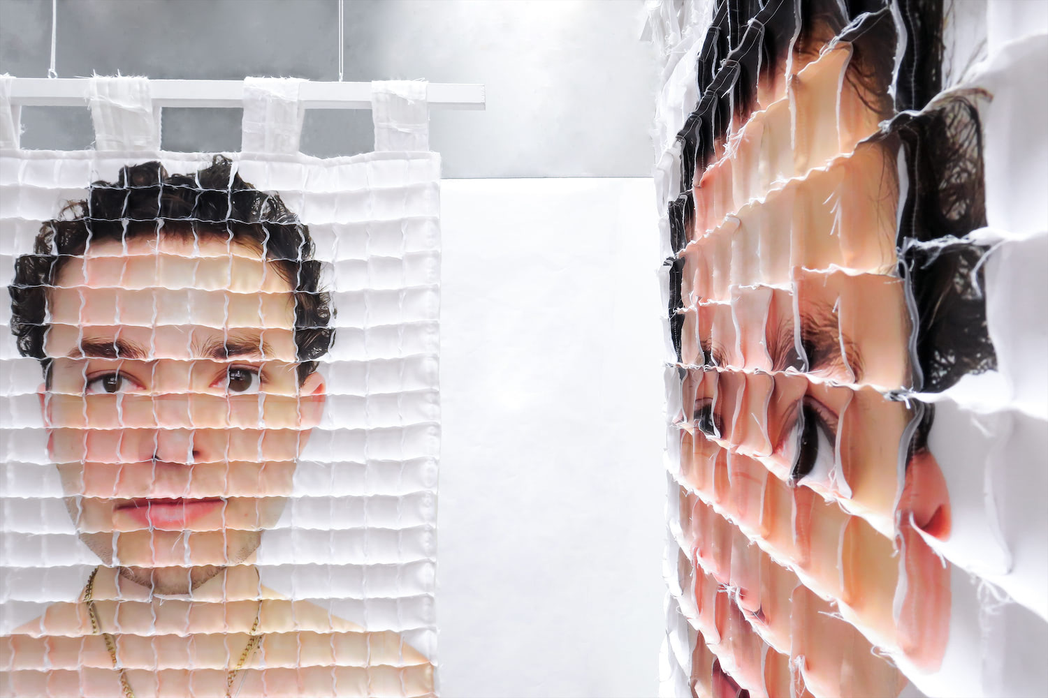 Two quilts are shown, both with the artist's face. Facing directly forward, the right side of the artist's face is visible. To the right, a close up view of a quilt is visible. The severe angle of the quilt emphasizes the gridded seams that cover the quilt.