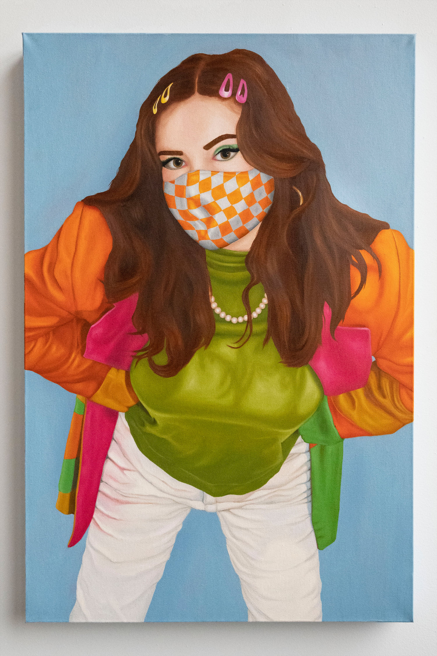 Sophie wearing a green, yellow, orange, and pink color blocked wool blazer over an olive green turtle neck and white jeans. Too accessorize, Sophie added a pearl necklace, yellow and pink hair clips and a white and orange checkered mask.