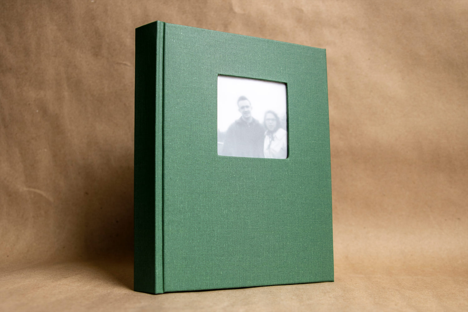 The front cover of a drum leaf style book with green bookcloth and an image of two people.