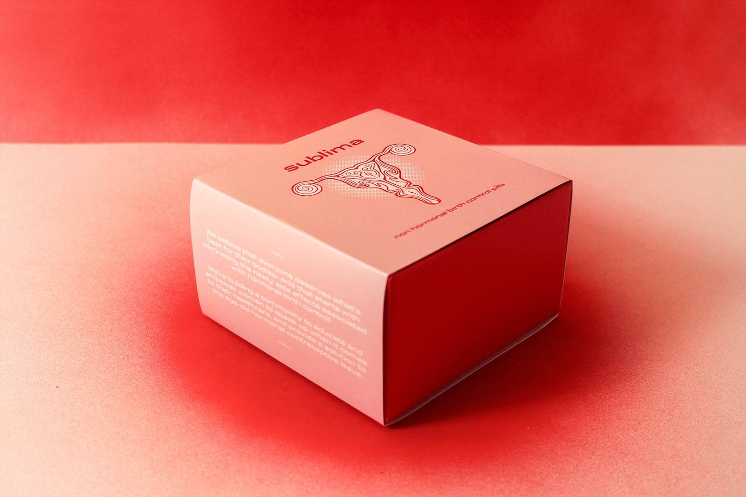 A side-on photo of Sublima's packaging box placed on a spray-painted red backdrop. The packaging consists of a light pink sleeve covering a red box. The top face of the sleeve shows Sublima's uterus logo with the words 
