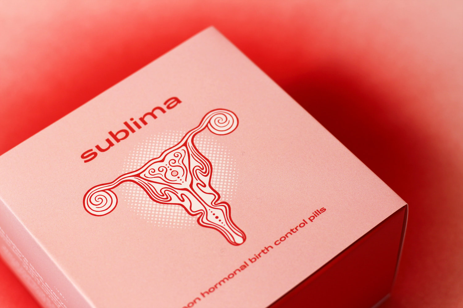 A close-up photo of Sublima's uterus logo on the front of the packaging box. The box is placed on a spray-painted red backdrop.