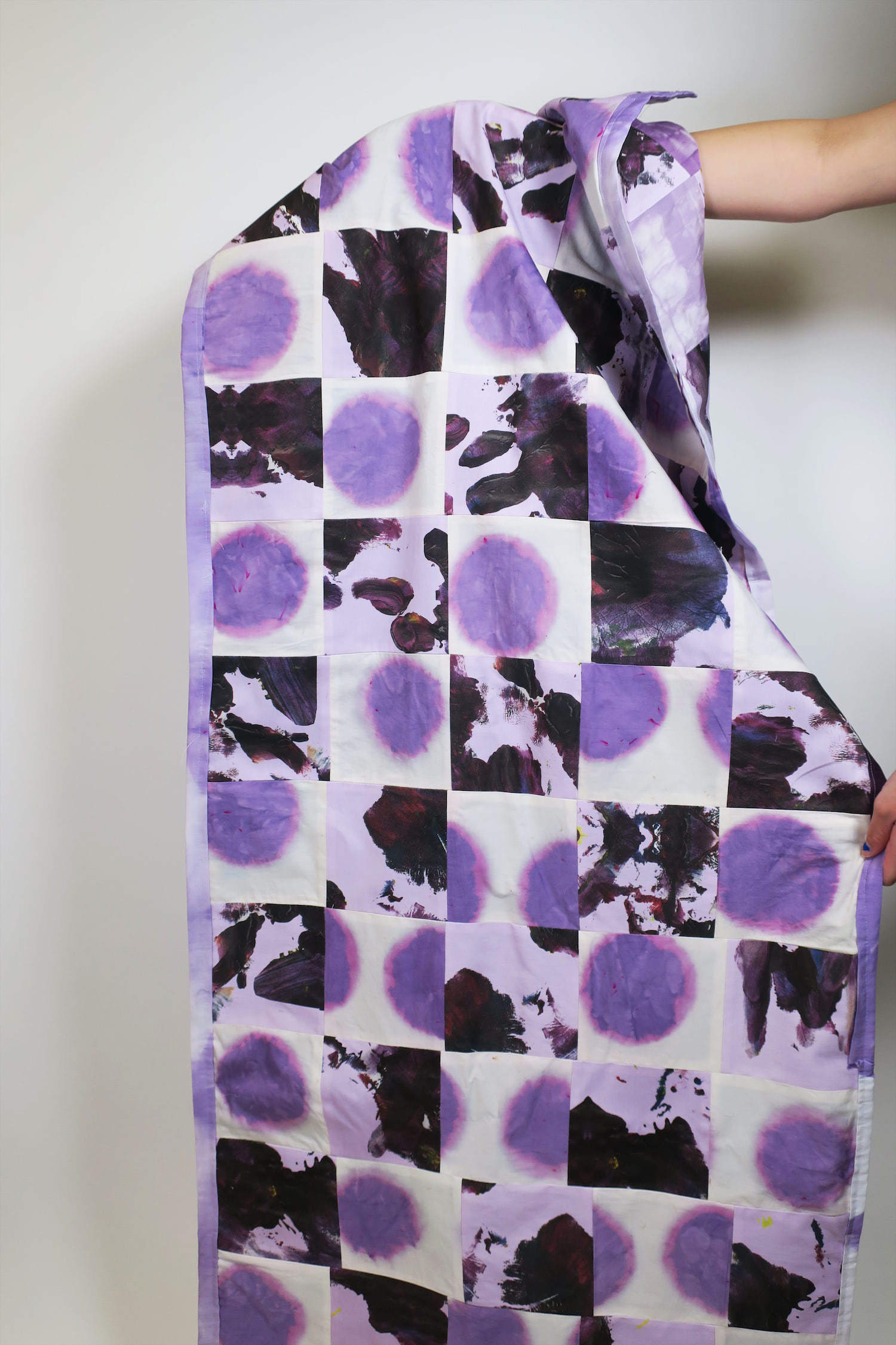 Studio shot of quilt in use showing colors, size and two sides of quilt.