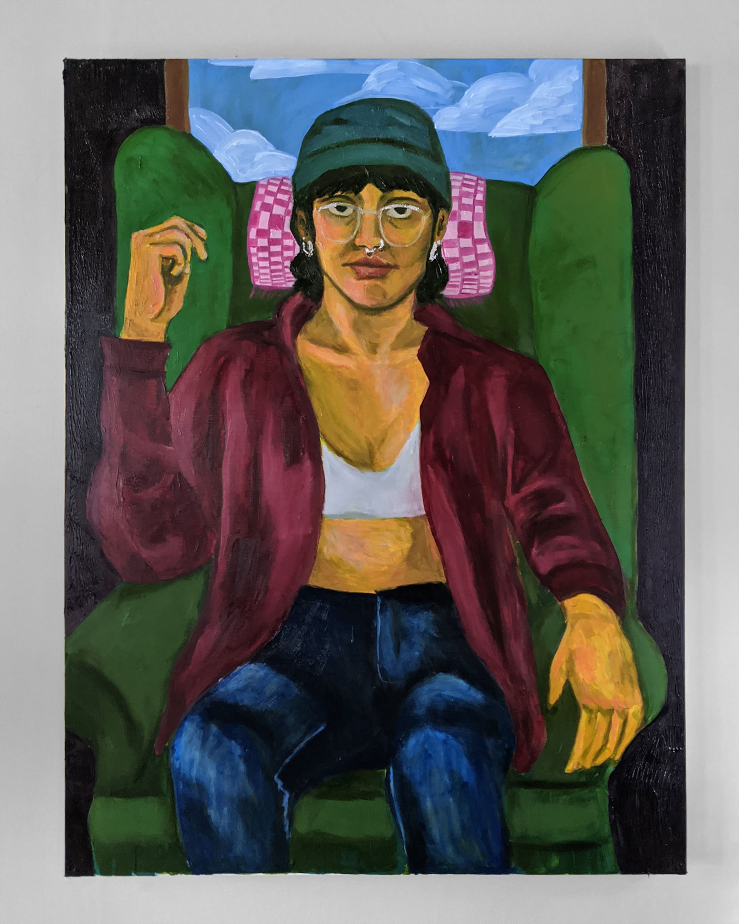 This is a painting of a woman sitting on a chair. She is sitting comfortably, with her fist casually in the air. She is looking directly at the audience with strength and confidence. Her skin is yellow and she is wearing men's clothing.