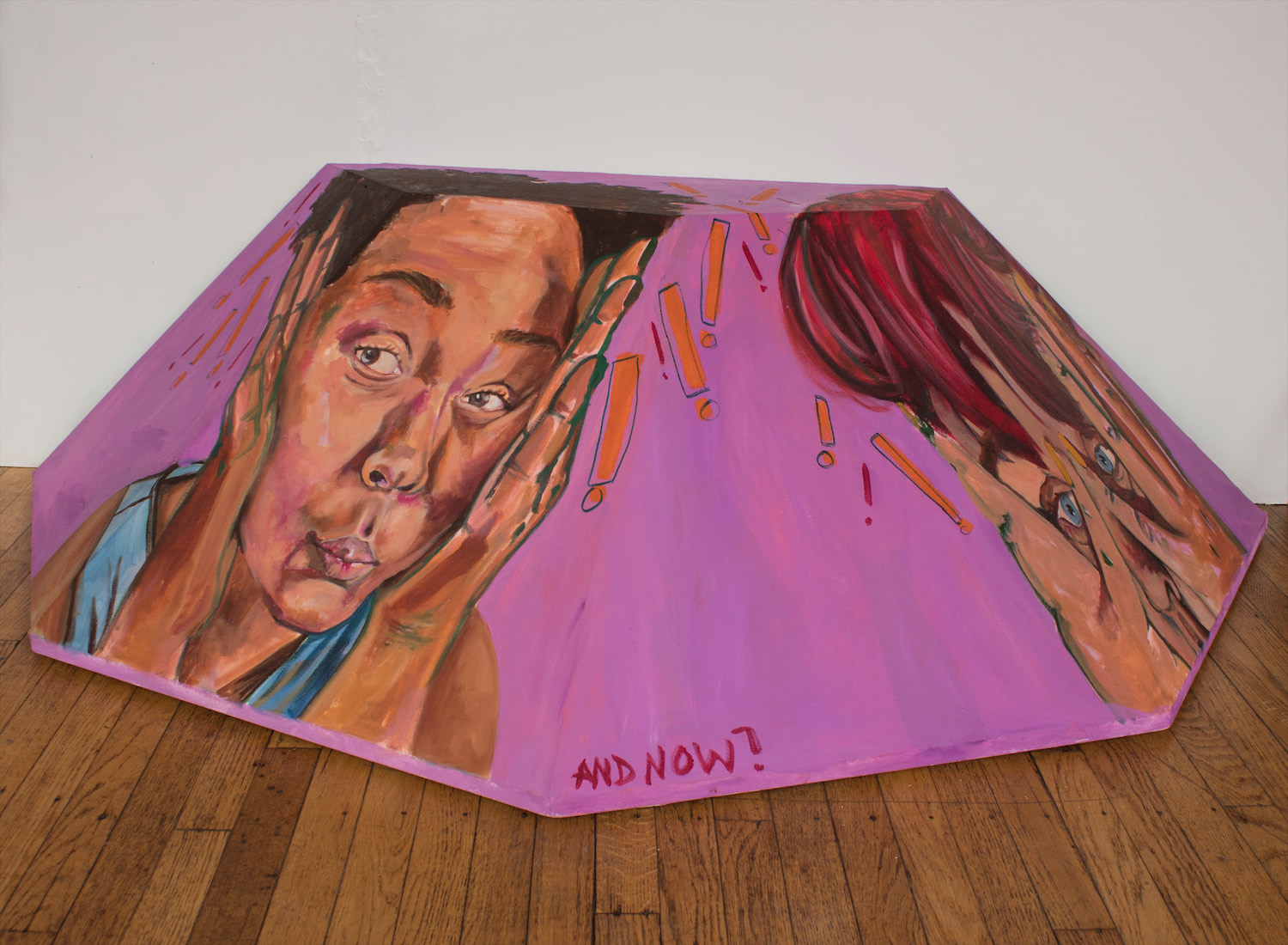 This shows the third artwork which is an octagonal shape cut in half and displayed on the floor and against the wall. There are two figures on this bright purple painted shaped canvas frame. Both are peeking through their hands to view whats in front of them. This is the first view that shows more of the figure on the left.